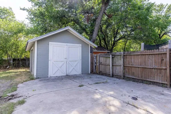 a view of backyard with large trees and wooden fence