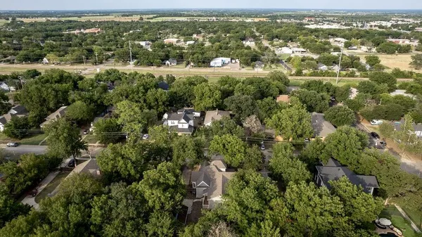 an aerial view of residential houses with outdoor space and trees