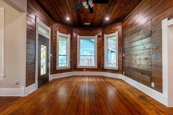 a view of an empty room with wooden floor and a window