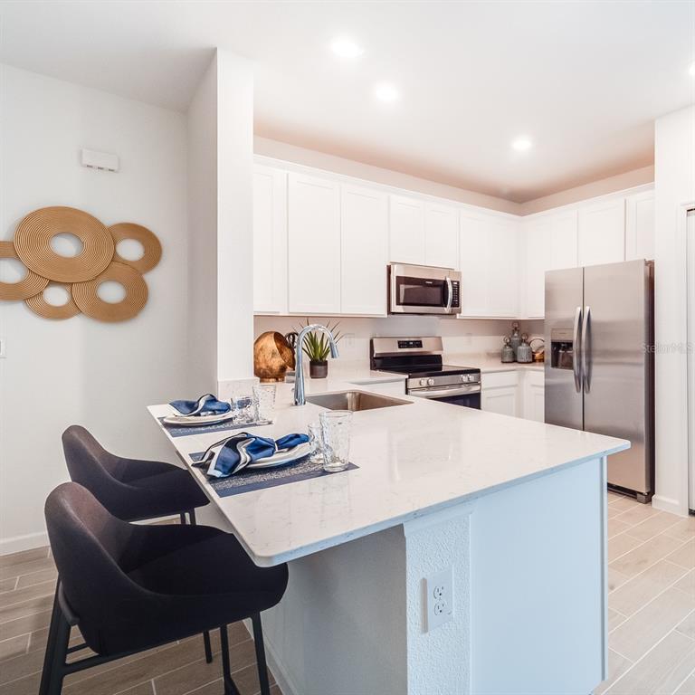 3639 Southeast 37th Ave Road Ocala, FL 34480 - Photo 45 of 61 a kitchen with stainless steel appliances granite countertop a stove refrigerator a sink dishwasher a dining table and chairs with wooden floor