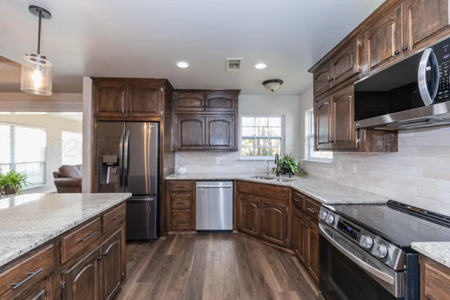a kitchen with stainless steel appliances granite countertop a sink stove and refrigerator