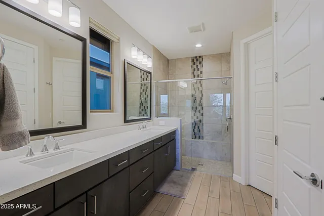 a spacious bathroom with a double vanity sink a large mirror and shower
