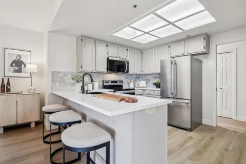 a kitchen with a refrigerator a stove a sink dishwasher a dining table and chairs with wooden floor