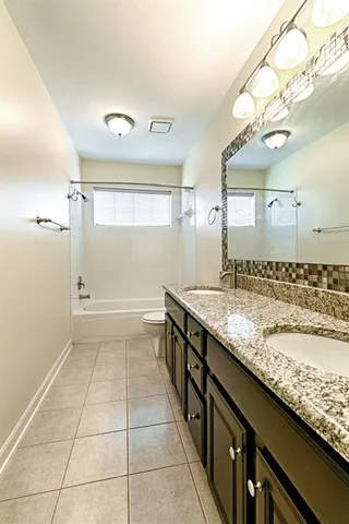 a bathroom with a granite countertop sink a toilet and a large mirror