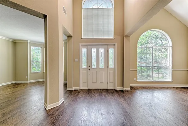 an empty room with wooden floor and windows