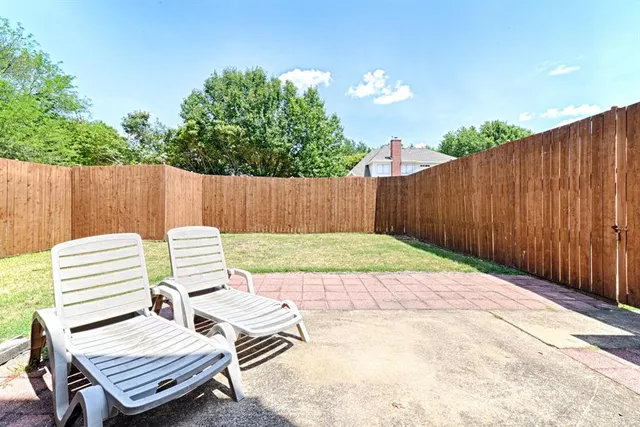 a view of a patio with table and chairs with wooden fence