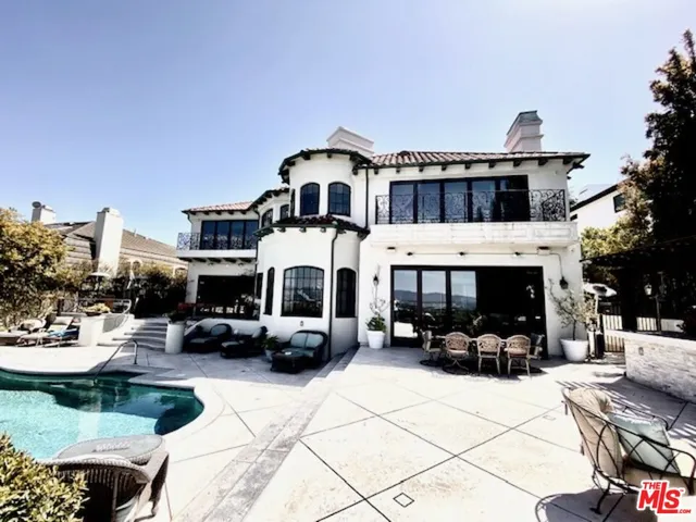 a view of a white house with a big yard and potted plants
