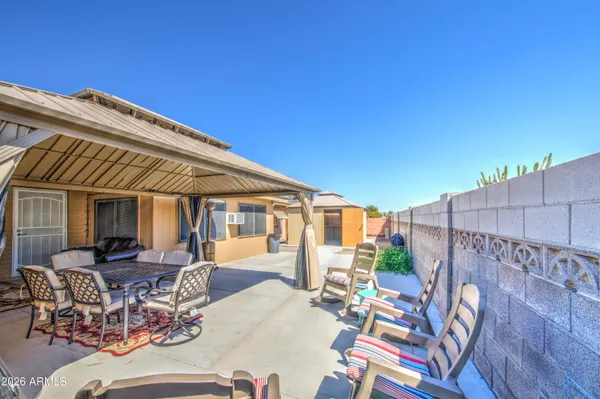 a view of a patio with couches and table and chairs with wooden floor and fence
