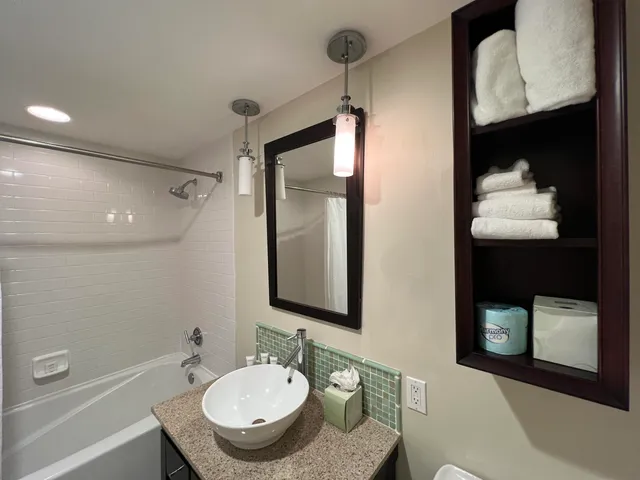 a bathroom with a granite countertop sink mirror and a bathtub