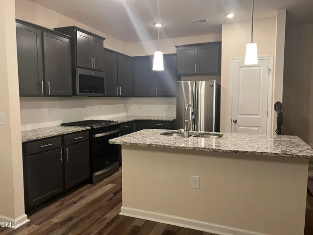 a kitchen with stainless steel appliances granite countertop a sink a stove and a refrigerator