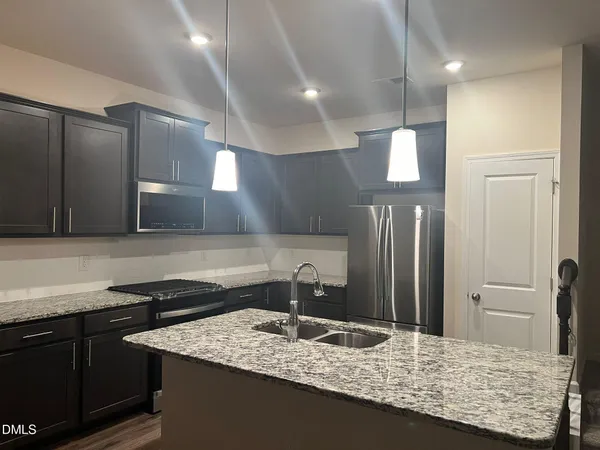 a kitchen with kitchen island granite countertop a sink and a refrigerator