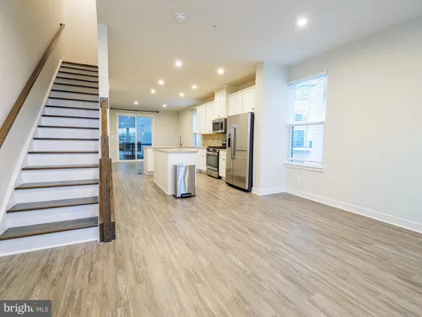 a view of kitchen with stainless steel appliances kitchen island refrigerator stove and wooden floor