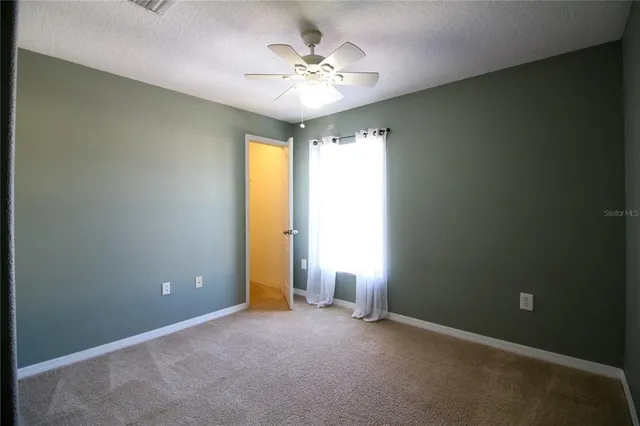 an empty room and a ceiling fan and window