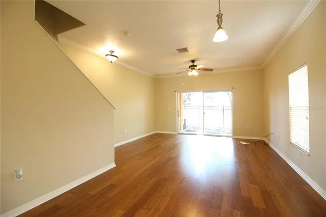 an empty room with wooden floor and windows