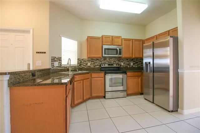 a kitchen with stainless steel appliances granite countertop a stove a sink and a refrigerator
