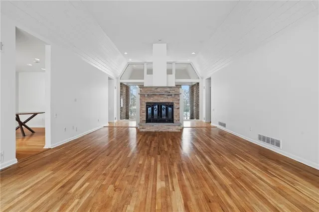 an empty room with wooden floor fireplace and windows
