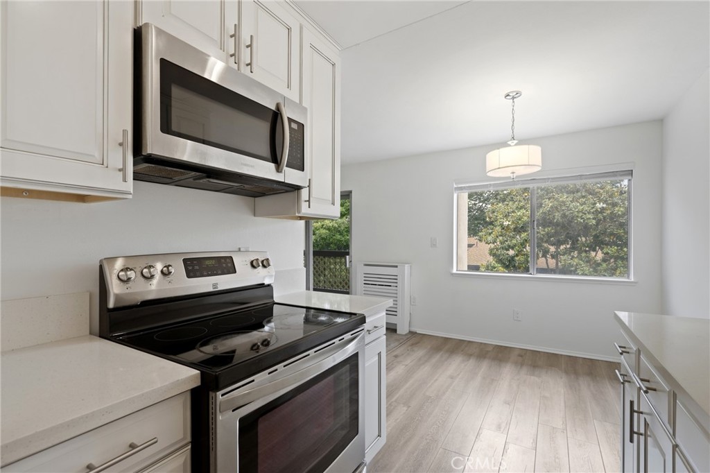 12200 Montecito Road, Unit D301 Seal Beach, CA 90740 - Photo 9 of 28 a kitchen with stainless steel appliances granite countertop a stove a microwave and a white cabinets