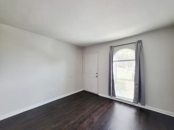 an empty room with wooden floor and window