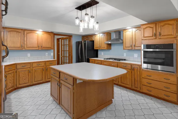 a kitchen with stainless steel appliances granite countertop a refrigerator a sink dishwasher and wooden cabinets with wooden floor