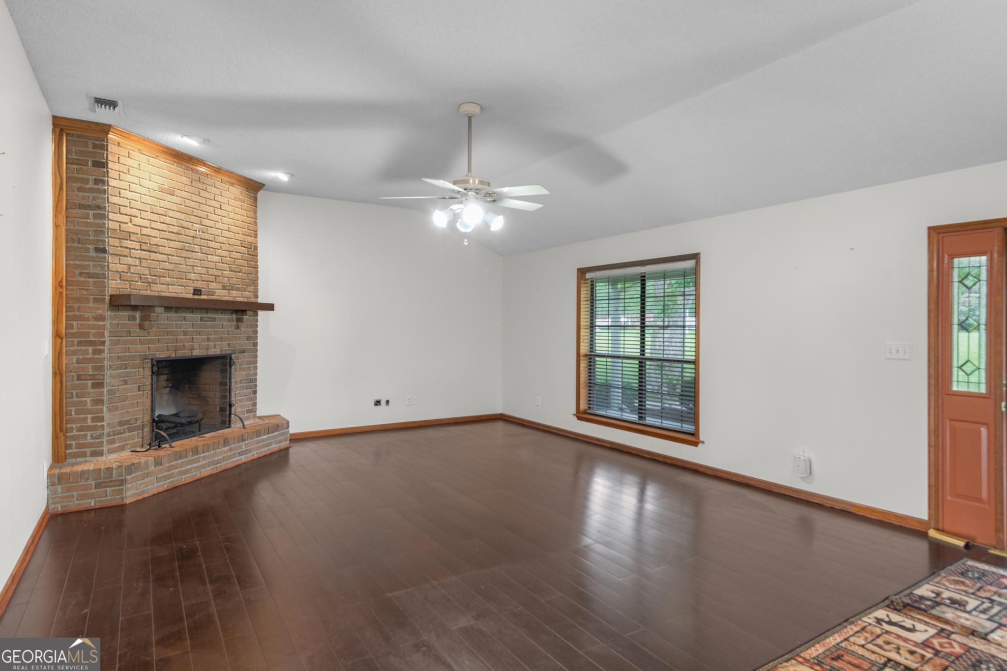 4909 Perry Road Claxton, GA 30417 - Photo 2 of 54 a view of an empty room with wooden floor fireplace and a window