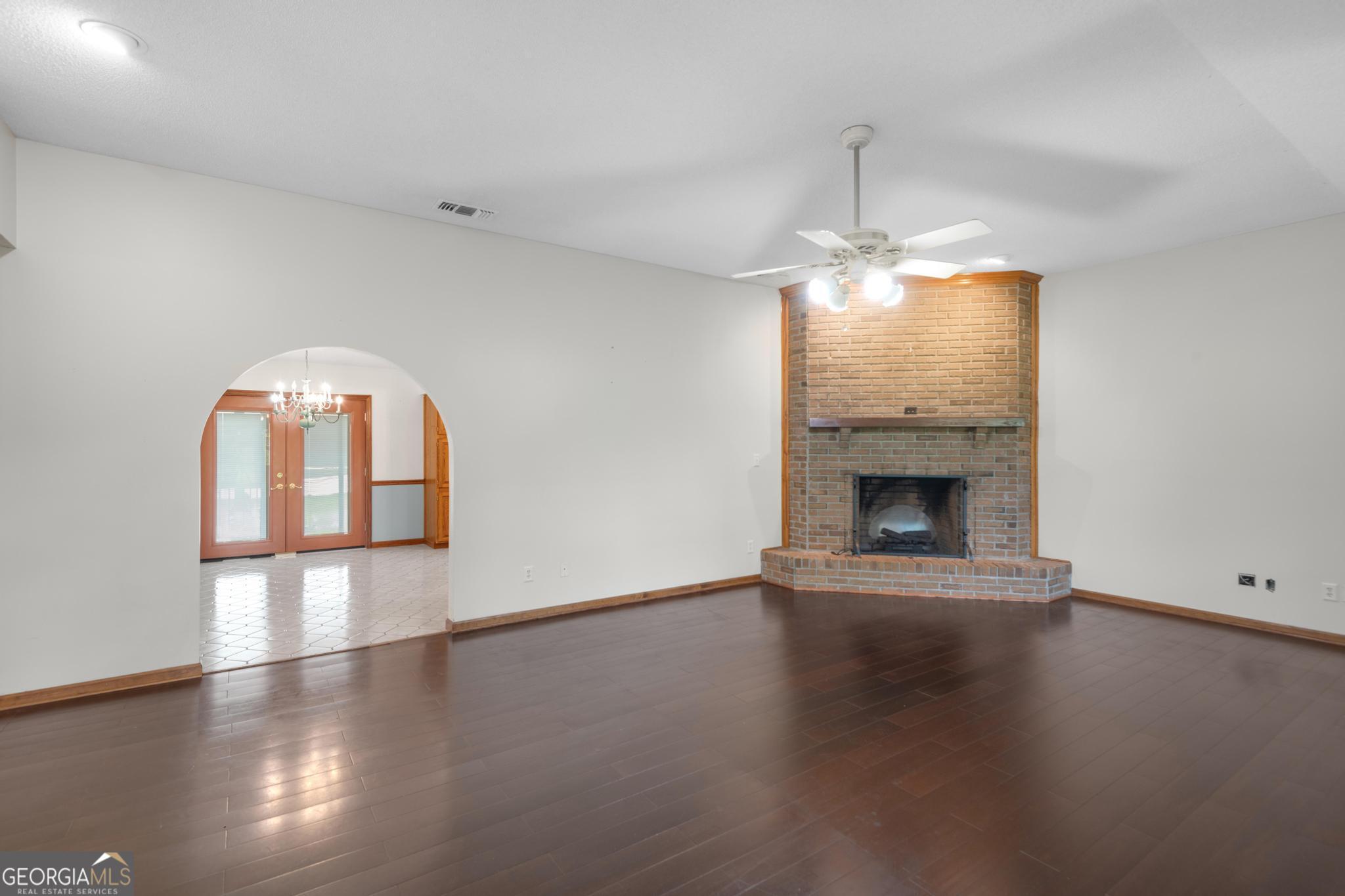 4909 Perry Road Claxton, GA 30417 - Photo 3 of 54 an empty room with wooden floor fireplace and windows