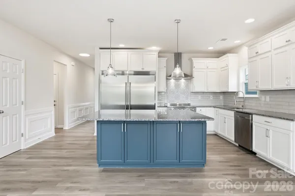 a open kitchen with kitchen island white cabinets and stainless steel appliances