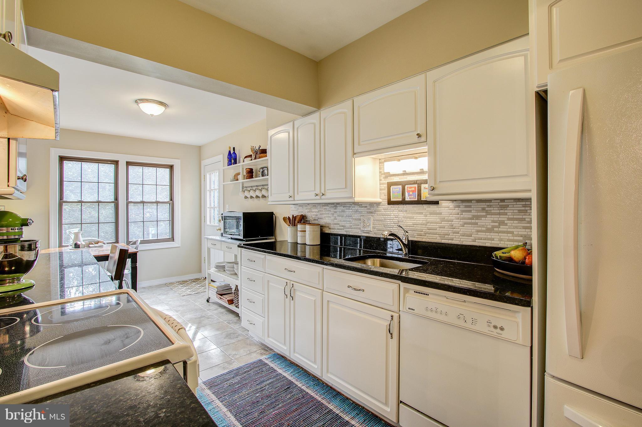 9929 Markham Street Silver Spring, MD 20901 - Photo 11 of 29 a large kitchen with granite countertop a sink a stove and cabinets