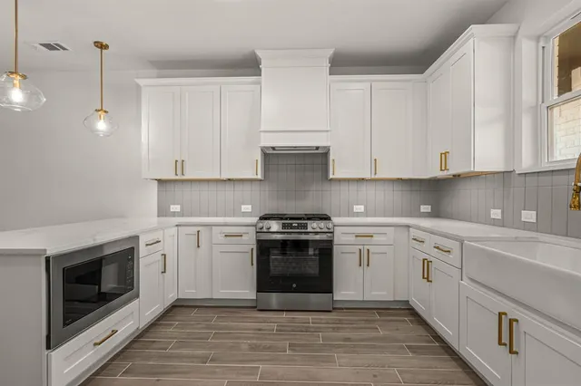 a kitchen with stainless steel appliances granite countertop a stove and white cabinets