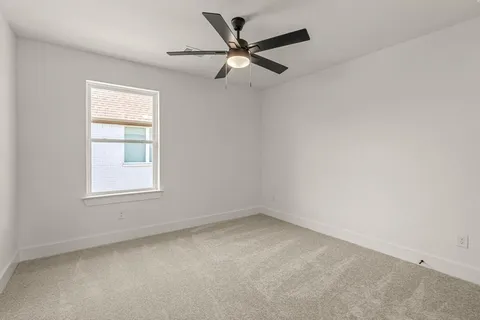 an empty room with a window and a fan