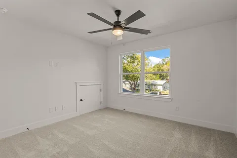 an empty room with a window and a ceiling fan