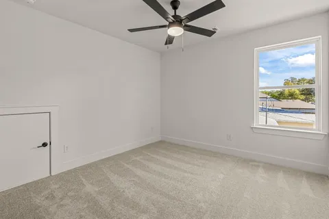 an empty room with a window and a fan