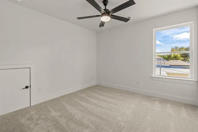 an empty room with a window and a fan