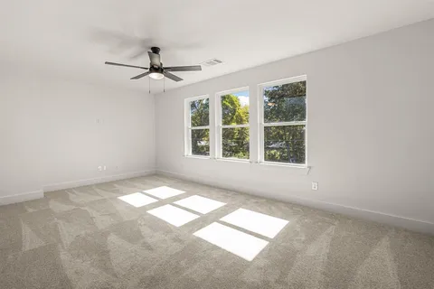 an empty room with windows and fan