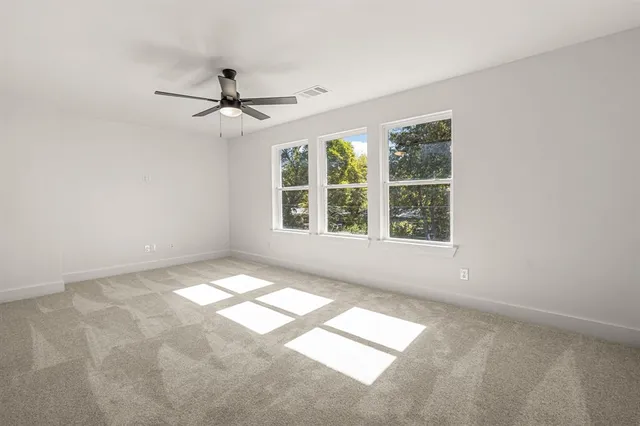 an empty room with windows and fan