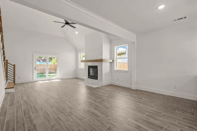 an empty room with wooden floor fireplace and windows