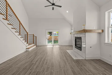 an empty room with wooden floor fireplace and windows