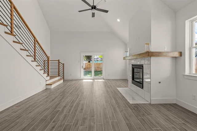 an empty room with wooden floor fireplace and windows