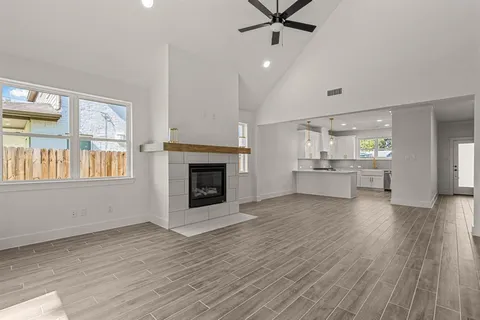 an empty room with wooden floor a fireplace and windows