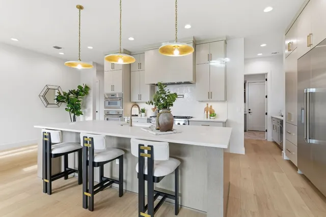 a kitchen with stainless steel appliances granite countertop a sink a stove and a wooden floors