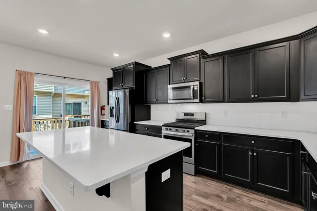 a kitchen with stainless steel appliances a stove a sink a microwave a refrigerator and cabinets