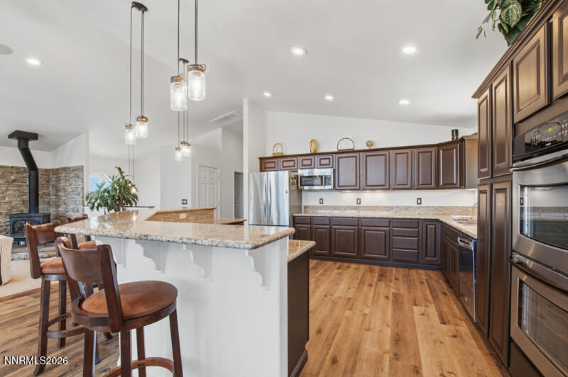 1367 Calavaras Road Reno, NV 89521 - Photo 6 of 26 a kitchen with stainless steel appliances kitchen island granite countertop a table chairs in it and wooden floors