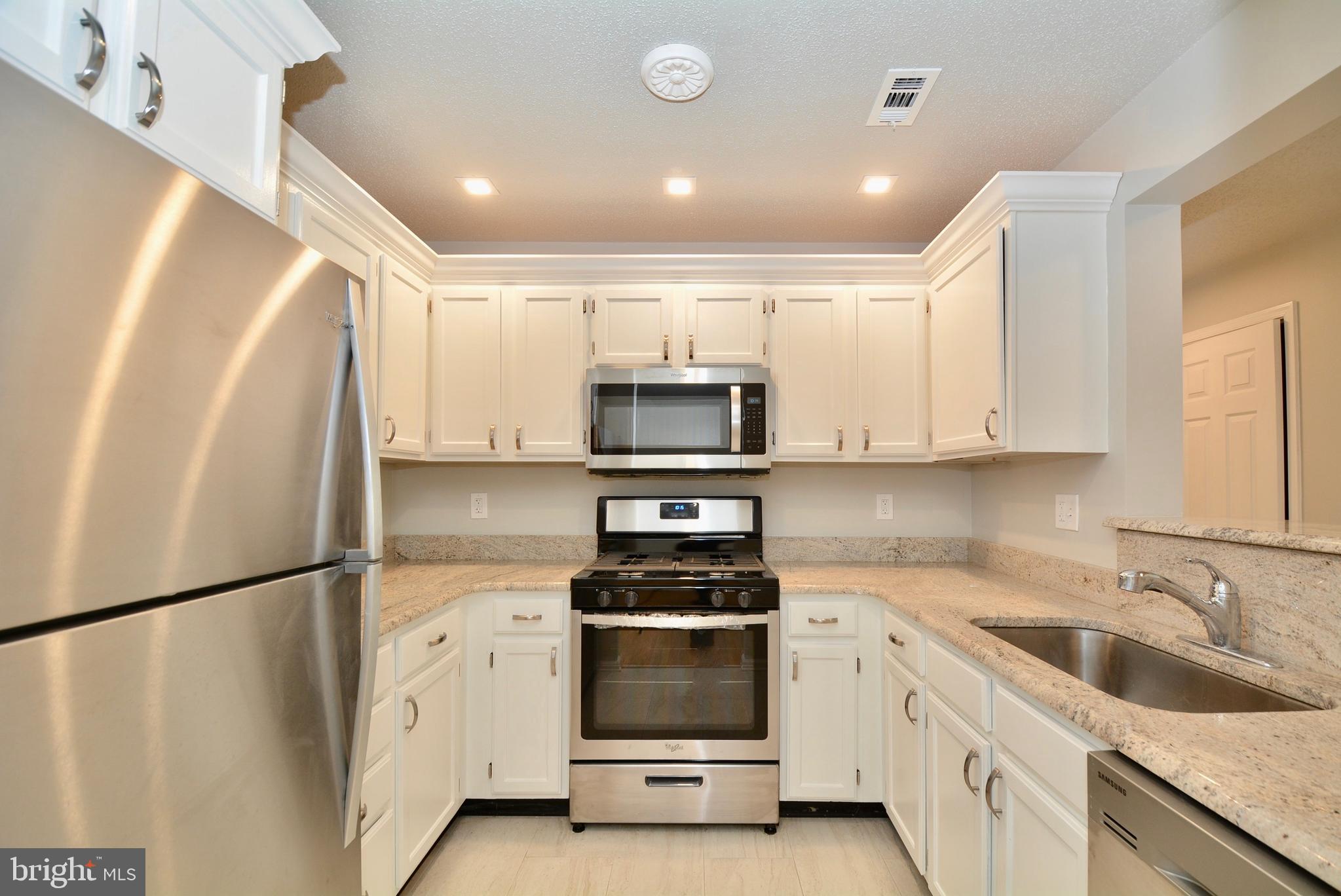12000 Taliesin Place, Unit 36 Reston, VA 20190 - Photo 5 of 36 a kitchen with granite countertop white cabinets and white appliances