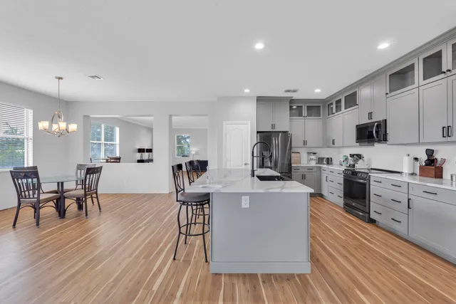 a kitchen with stainless steel appliances a dining table chairs stove microwave and cabinets