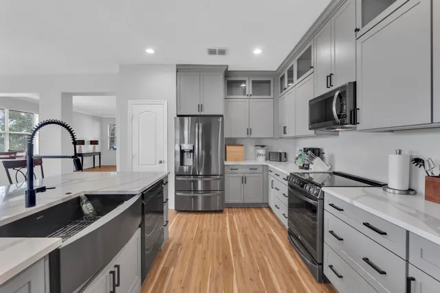 a kitchen with granite countertop a stove top oven a sink dishwasher a refrigerator and cabinets with wooden floor