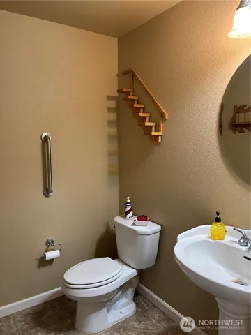 a bathroom with a toilet and a wooden floor
