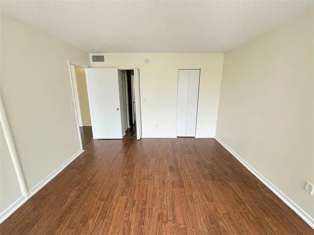 an empty room with wooden floor and closet