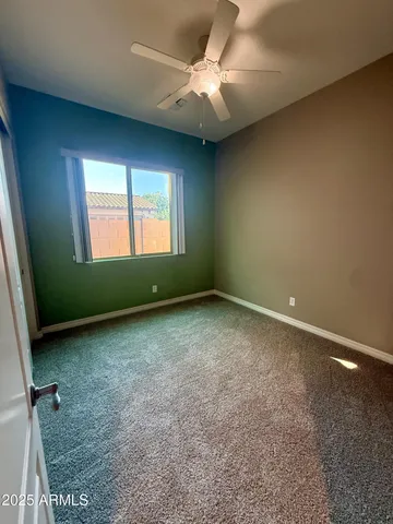an empty room with a ceiling fan and window