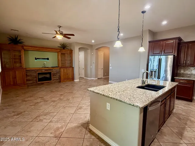 a kitchen with kitchen island granite countertop a sink a counter top space appliances and cabinets