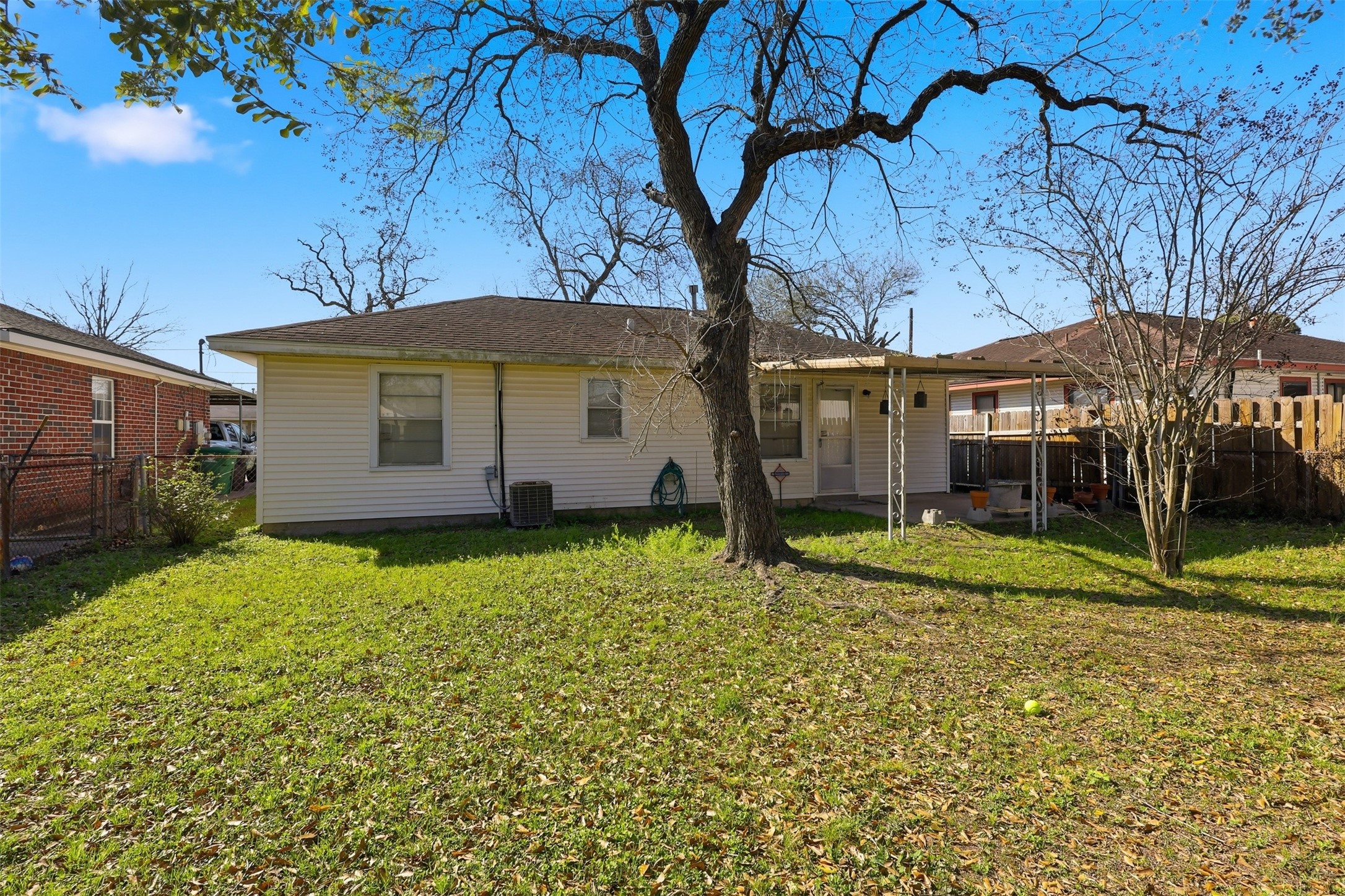 5707 Waltrip Street Houston, TX 77087 - Photo 14 of 15 Cozy backyard with a mature tree and well-maintained lawn, offering a covered patio ideal for relaxation. The space is fenced, providing privacy and a safe area for outdoor activities.