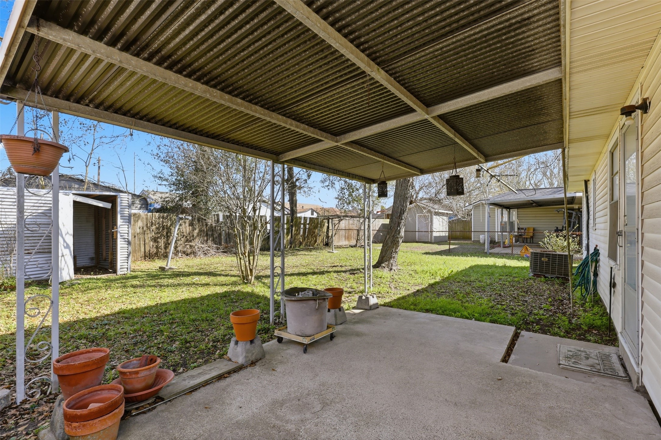 5707 Waltrip Street Houston, TX 77087 - Photo 15 of 15 This photo showcases a backyard with a covered patio area, perfect for outdoor relaxation. The yard is spacious, featuring a fenced perimeter, a few trees, and a storage shed, offering plenty of potential for gardening or entertaining.